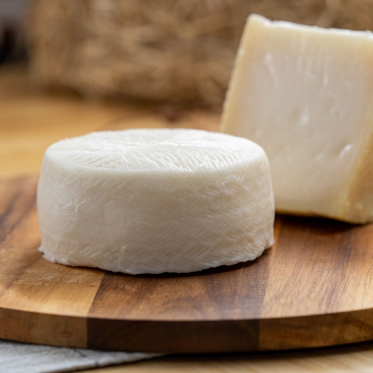 Queso de cabra semicurado y queso curado enteros sobre tabla de madera